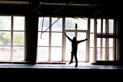 Full length of man standing in window. spreading his hands flapping and trying to lift off. 