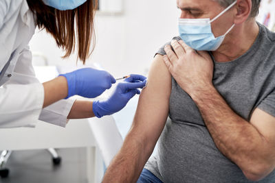 Midsection of doctor injecting syringe to patient