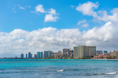 Sea by buildings against sky in city