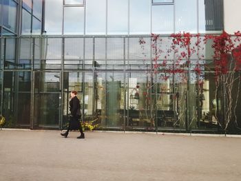 Full length rear view of man walking on modern building