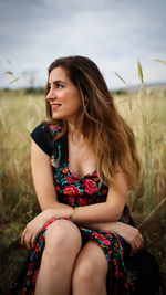 Portrait of beautiful young woman sitting on land