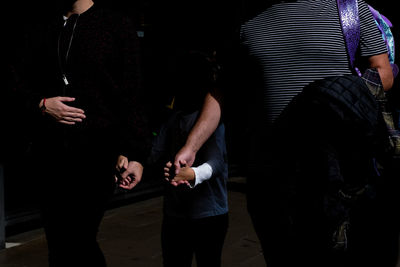 Midsection of family holding hands walking on street