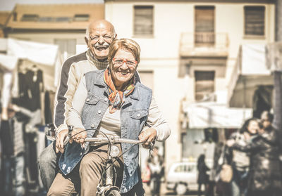 Portrait of senior couple on bicycle at street in city