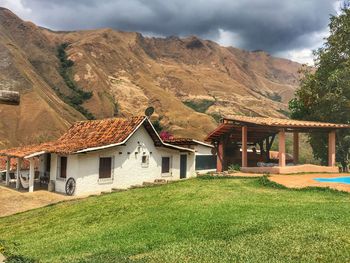 House on field by mountain against sky