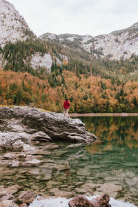 Rear view of man standing by lake against forest