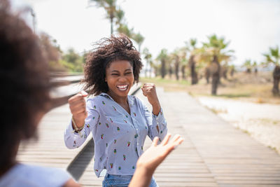 Happy young woman holding umbrella while standing on footpath