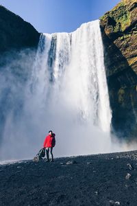 Man standing against waterfall