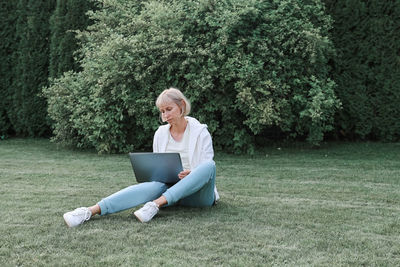 Full length of woman sitting on mobile phone