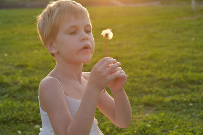 Portrait of boy holding flower on field