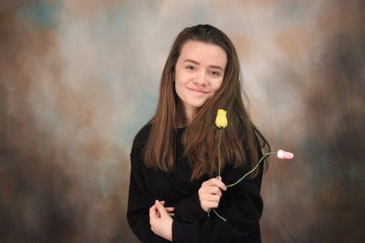 Portrait of smiling woman standing against wall