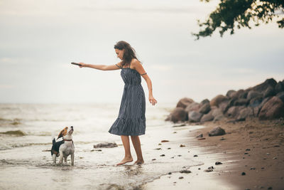 Woman with dog on beach against sky