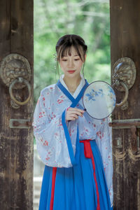 Portrait of young woman holding umbrella standing outdoors