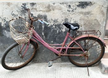 Rusty bicycle parked against wall