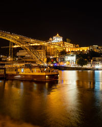 Illuminated buildings by river against sky at night