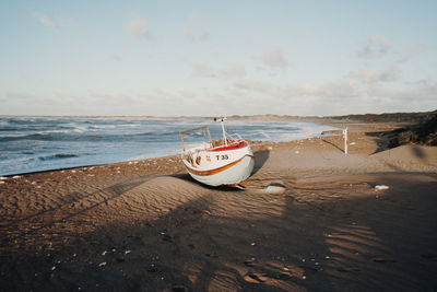 Boat moored on beach against sky