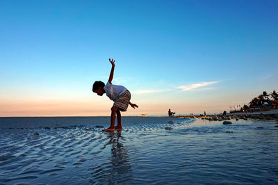 Full length of boy standing on beach against clear sky