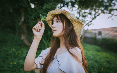 Portrait of woman wearing hat standing against plants