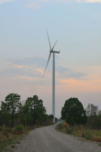 Wind turbines on field against sky during sunset