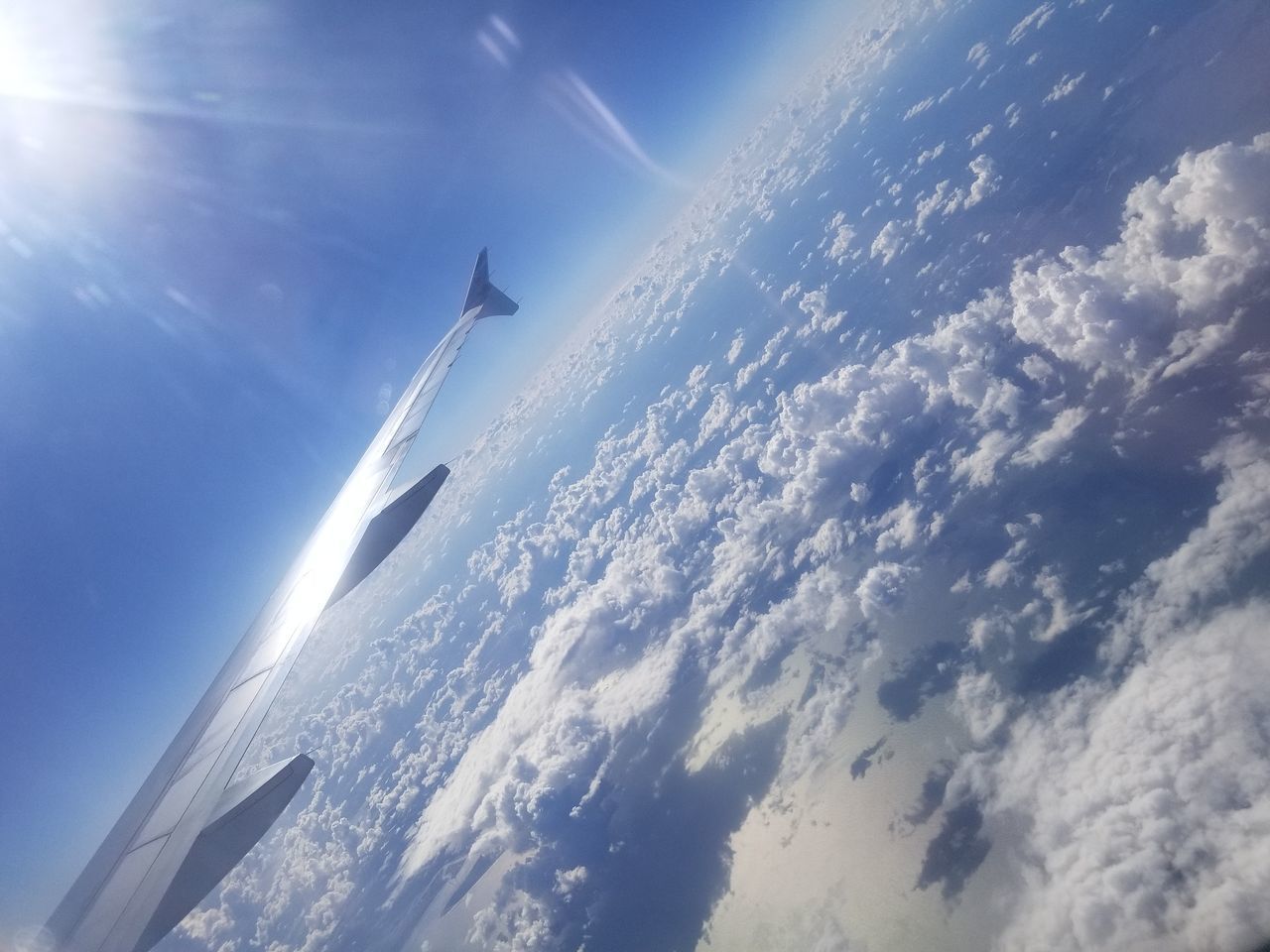 LOW ANGLE VIEW OF AIRPLANE FLYING OVER CLOUDS AGAINST SKY