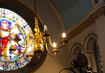 Low angle view of lit chandelier in church