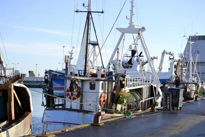 Boats moored at harbor against sky