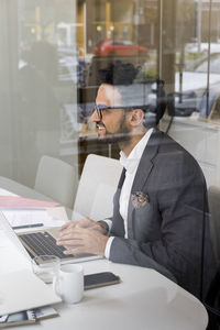 Side view of male real estate agent using laptop in office