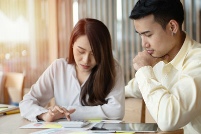 Young couple looking at camera while sitting on table