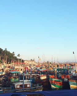 Boats moored at harbor against clear sky