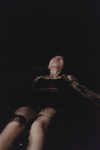 Low angle view of woman looking up against black background