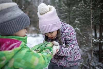Cute sibling holding hands standing outdoors during winter