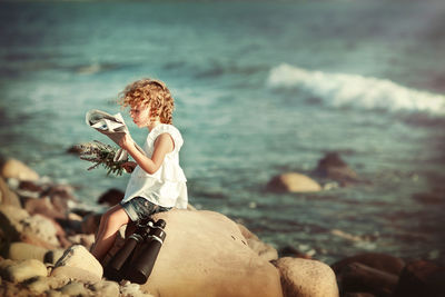 Woman sitting on rock at beach