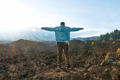 Man enjoying freedom with open hands,while admiring panoramic view of snowy summits of volcano etna.