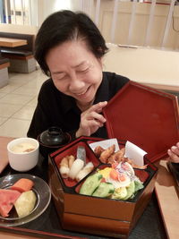 Smiling senior woman looking at foods in container on table 
