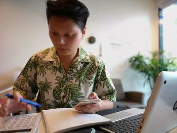 Man using mobile phone while sitting on table