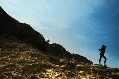 Low angle view of man standing on mountain against clear sky