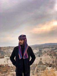 Portrait of young man standing on mountain against sky