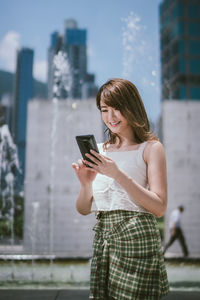 Young woman using mobile phone in city