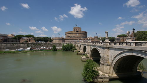 Arch bridge over river against cloudy sky