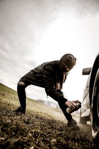 Disguised woman spraying color on tire of car