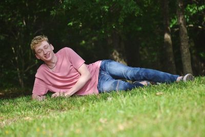 Teenage boy looking away while lying on grass at park