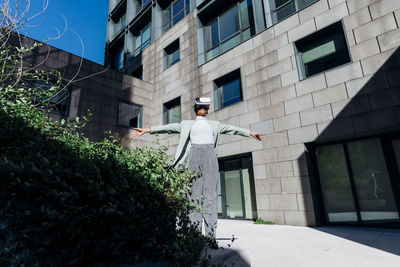 Businesswoman with arms outstretched standing in front of office building