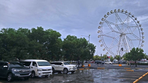 Cars parked by road against sky in city