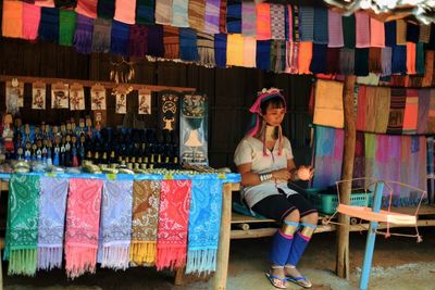 Long neck tribe woman in traditional clothing sitting at market