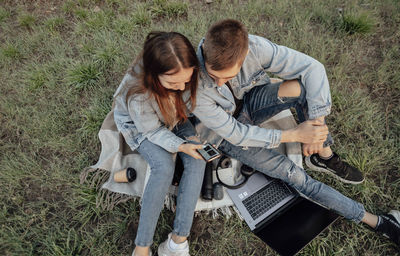 Man and a woman with a laptop and tablet while working using laptop, sitting in park