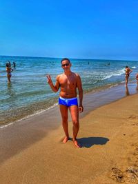 Full length of friends standing on beach