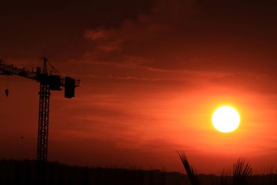 Silhouette of crane against dramatic sky during sunset