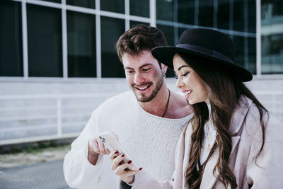 Portrait of a smiling young couple holding camera outdoors