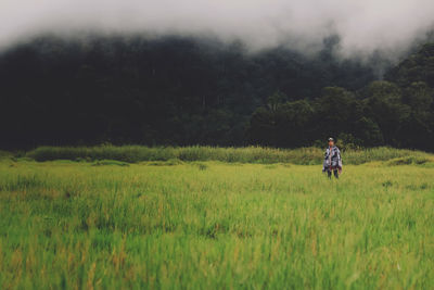 Man standing on agricultural field during foggy weather