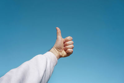Cropped image of hand against clear blue sky