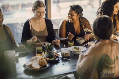 Female friends talking to each other while having breakfast at retreat center